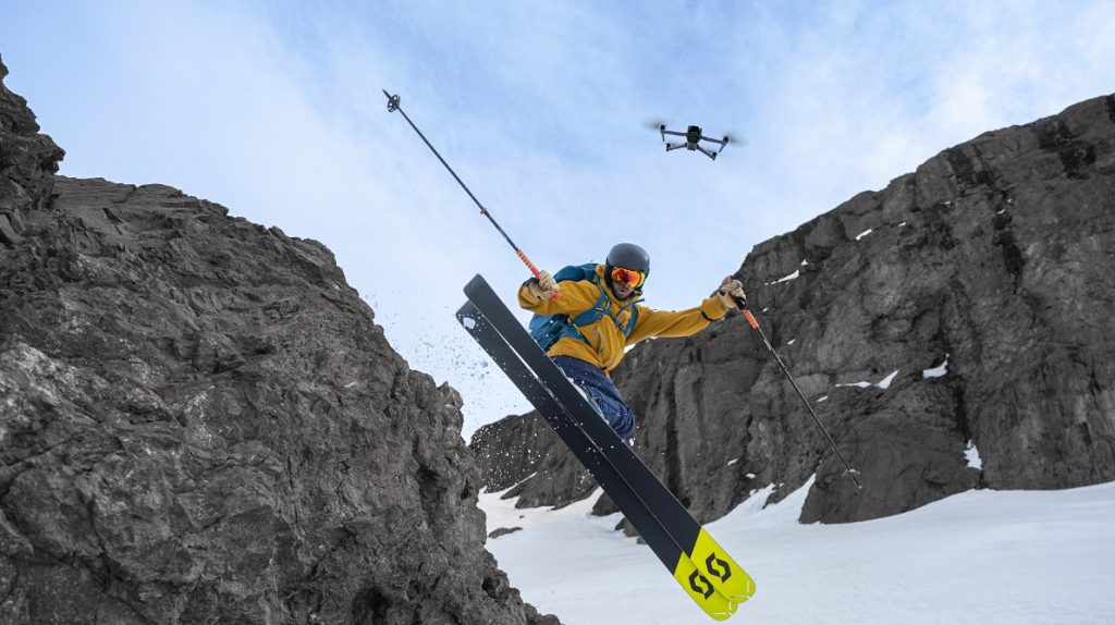 Skifahrer springt an Fels und wird von DJI Air 3S Drohne gefilmt