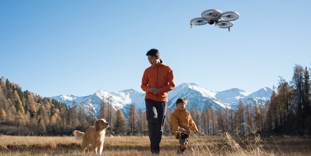 DJI Flip Drohne filmt Familie mit Hund vor Berglandschaft